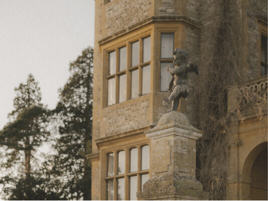 photo of the manor building. a statue on a pedestal in front of the corner of the building